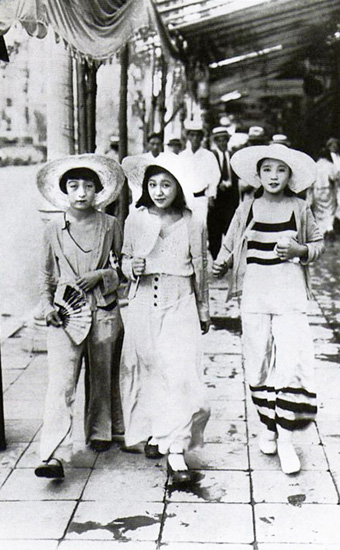 白い洋服に身をつつみ街を歩く三人の女子